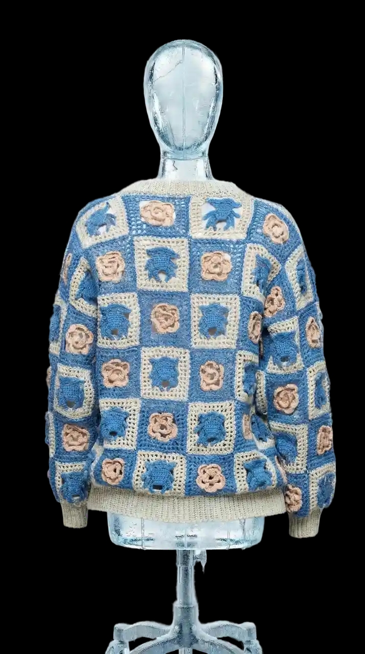 Кардиган связан крючком из хлопка в технике бабушкин квадрат. Модель собрана из отдельных квадратов с рельефными мотивами — фирменные Чихпауки и розы чередуются, формируя узнаваемый графический орнамент.
Свободный унисекс-силуэт, V-образный вырез и застёжка на декоративные пуговицы в виде паутины делают модель удобной и выразительной.
Серо-синяя цветовая гамма в сочетании с бежевыми элементами подчёркивает фактуру ручной вязки и делает мотивы Чихпауков особенно выразительными — графично, спокойно и современно.