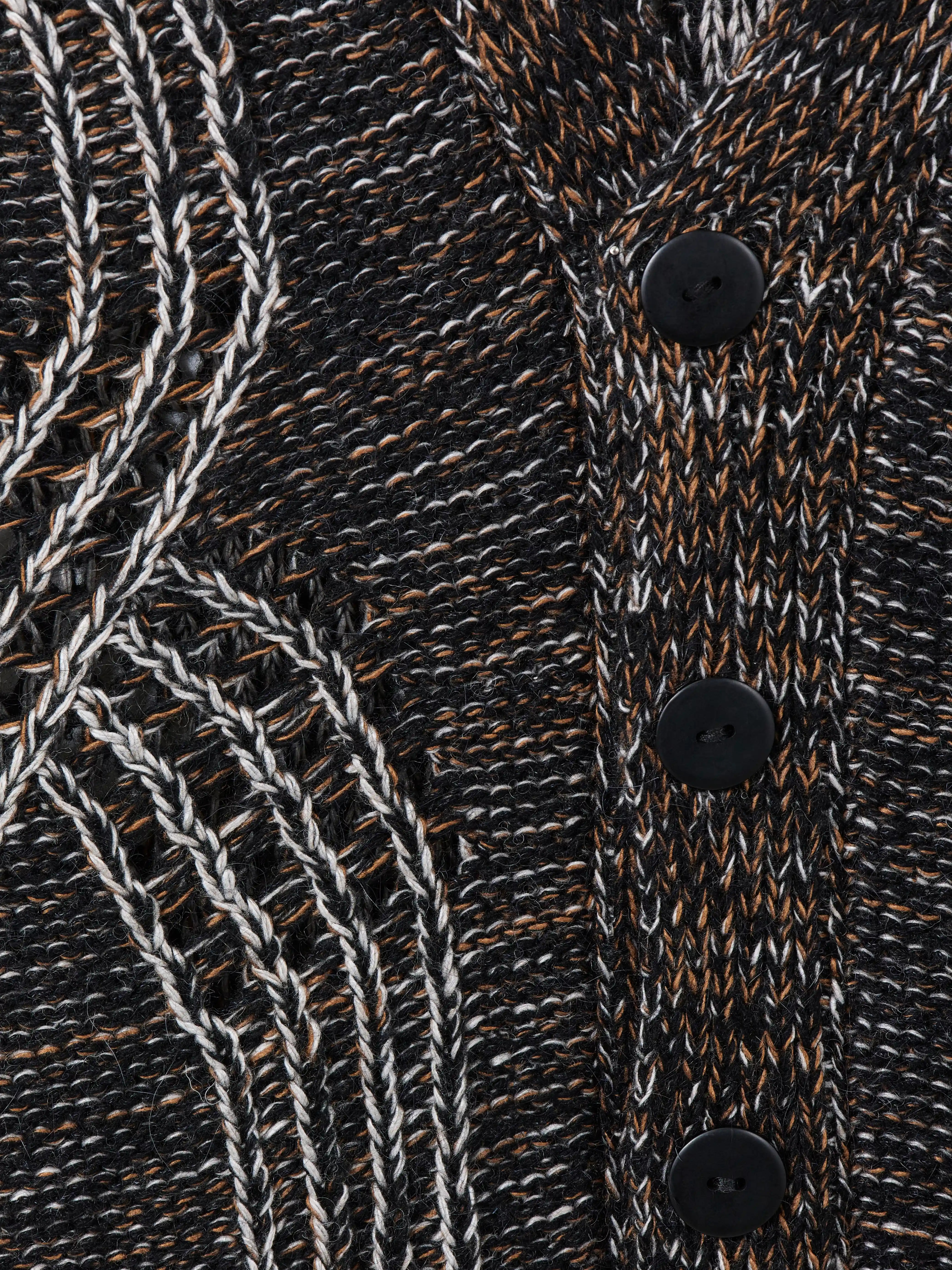 Кардиган на пуговицах выполнен в технике платировочного вязания, которая создаёт выразительный контраст между рисунком и основным полотном. Благодаря эффекту инверсии цвета модель можно носить на обе стороны. Фактурные косы с воздушным ажуром задают эффектный характер образа, что позволяет легко сочетать кардиган с лаконичными базовыми вещами.
Кардиган связан из высококачественной итальянской пряжи: натуральная шерсть в составе дополнена вискозой и нежным мохером. Такой состав вместе со свободным силуэтом обеспечивает высокий комфорт в носке. Каждое изделие проходит специальный цикл технологической стирки с использованием особых составов — процедура раскрывает структуру волокон, делая полотно мягким и приятным на ощупь.
В коллекции модель представлена в монохромной гамме: в полотне сочетаются нити чёрного, коричневого и светло-серого оттенков.